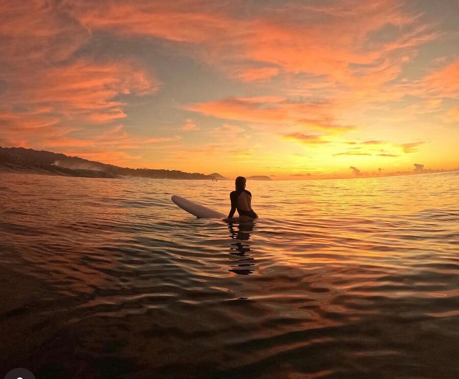 Stephanie Signorelli on a longboard at sunset off the windward coast of Oʻahu